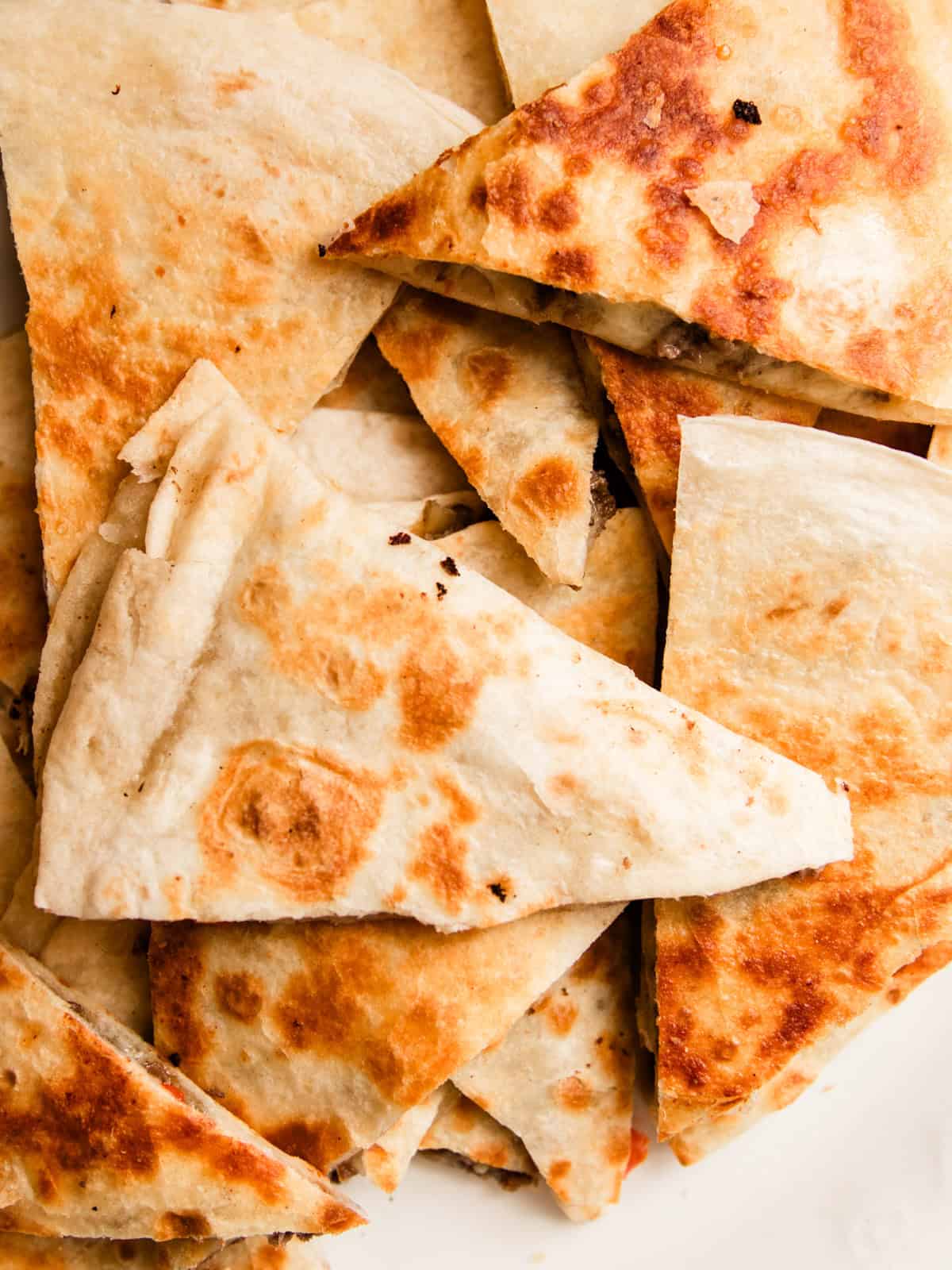 Looking down on a plate of venison quesadillas cut into triangles.