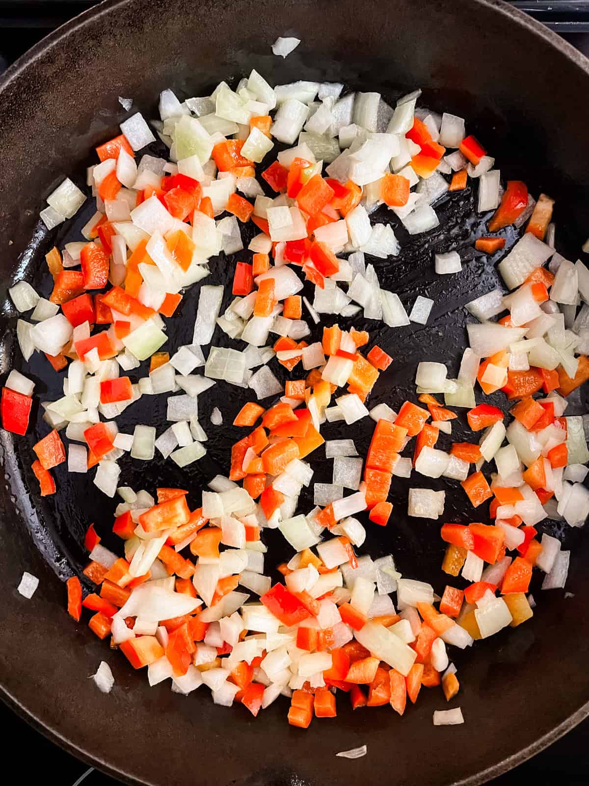 Sauteing onions and peppers in a cast iron skillet.