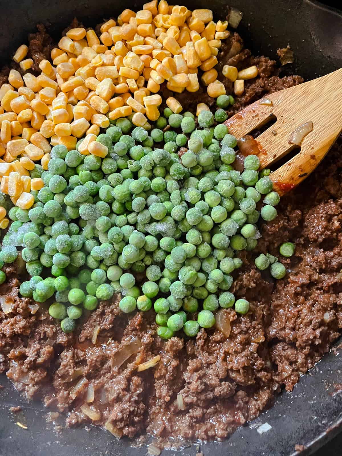 Cooked venison with frozen carrots and peas.
