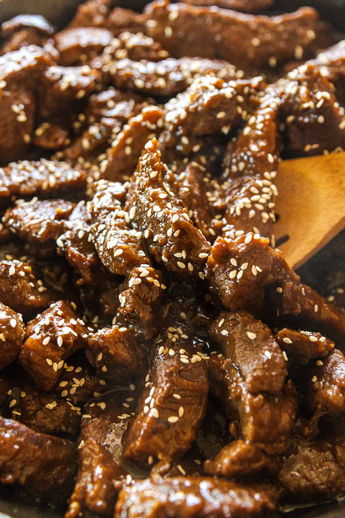 Scooping garlic ginger venison with a wooden spoon.