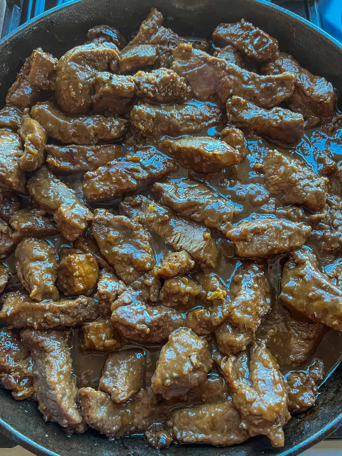 Cooked venison in a cast iron skillet with the sauce.