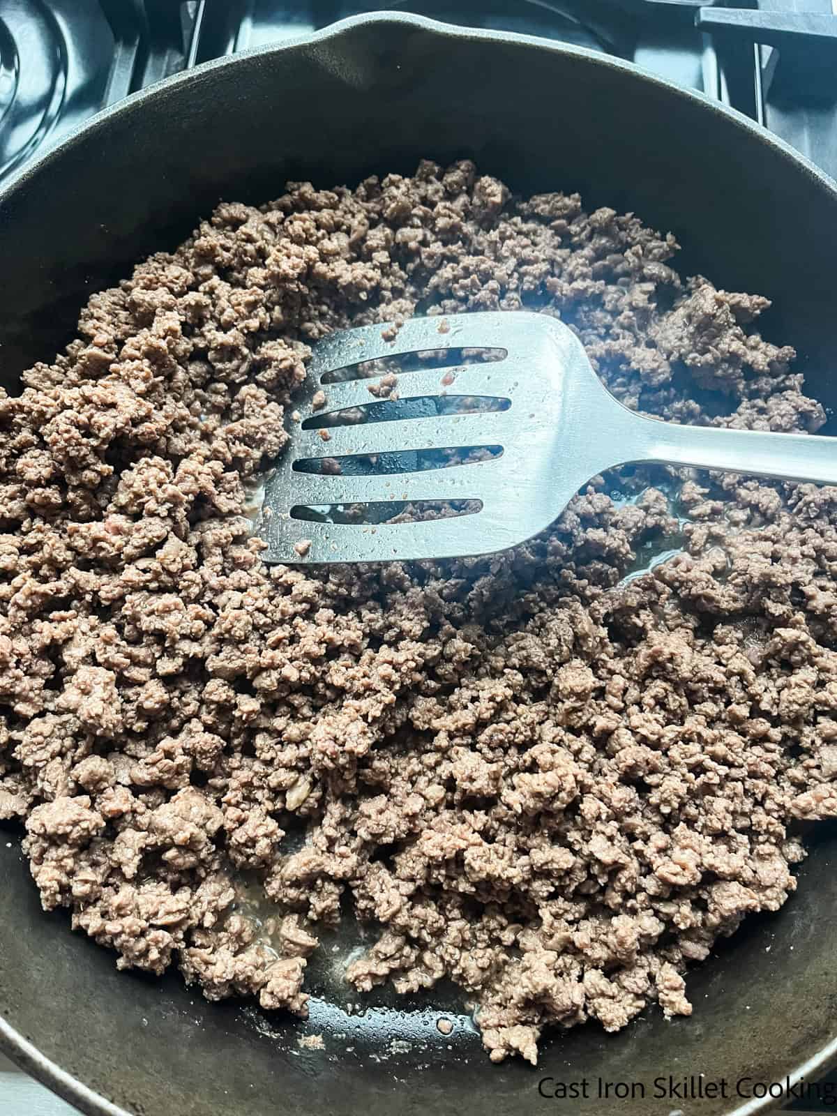 Browning ground venison in a cast iron skillet.