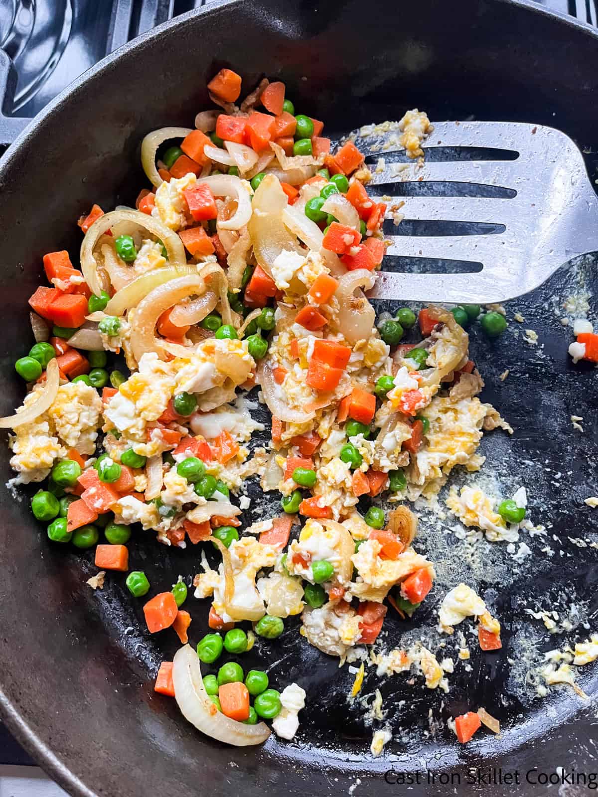 Scrambling eggs in a cast iron skillet with the fried rice veggies.