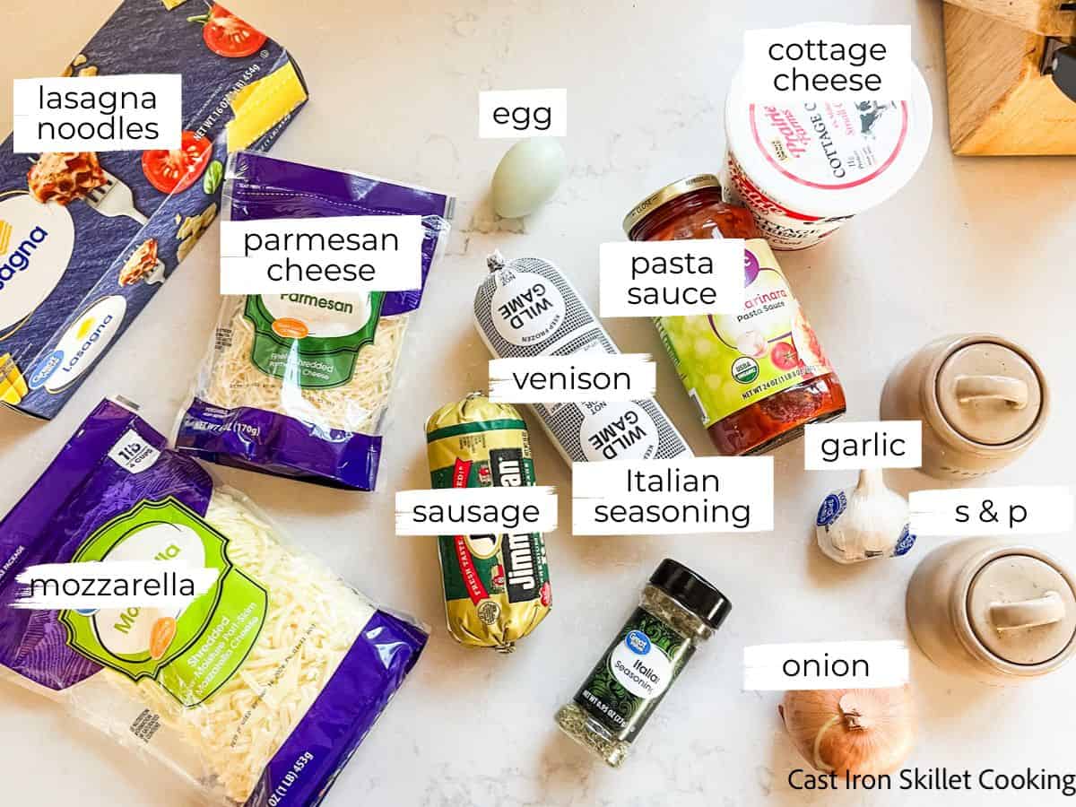 Venison lasagna ingredients labeled on a white table.
