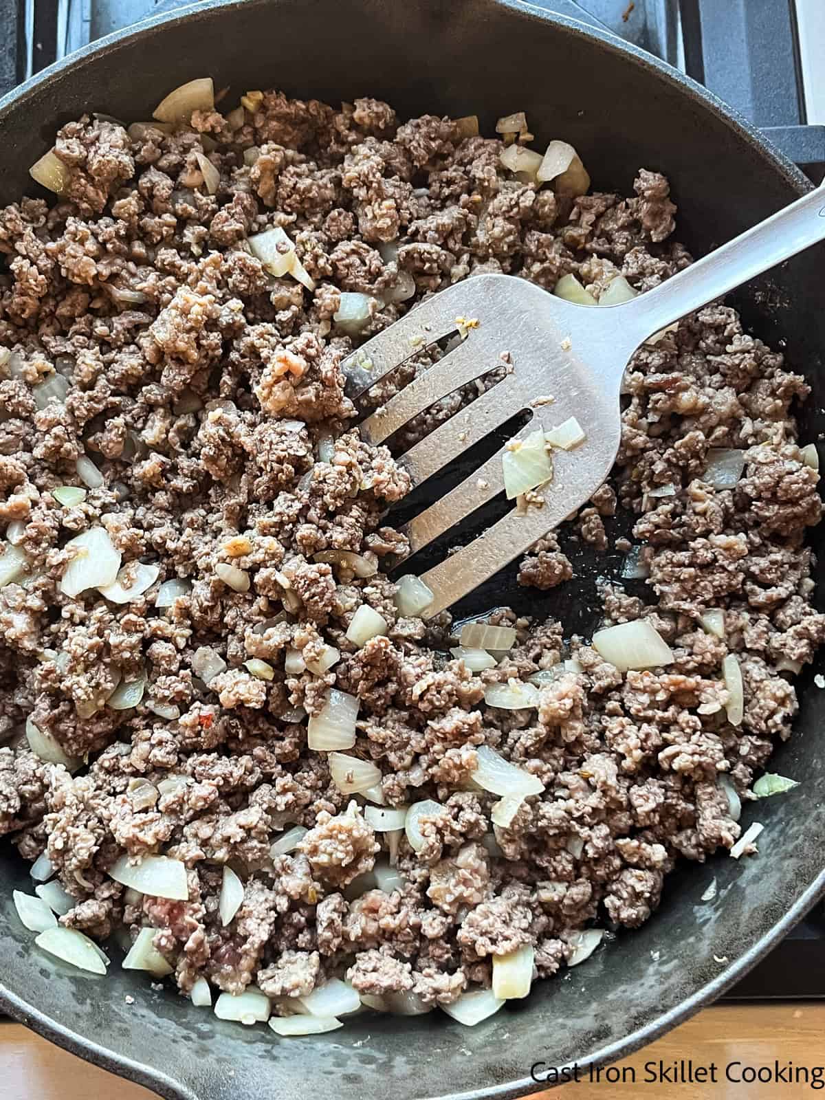Browned meat and onions in a cast iron skillet.