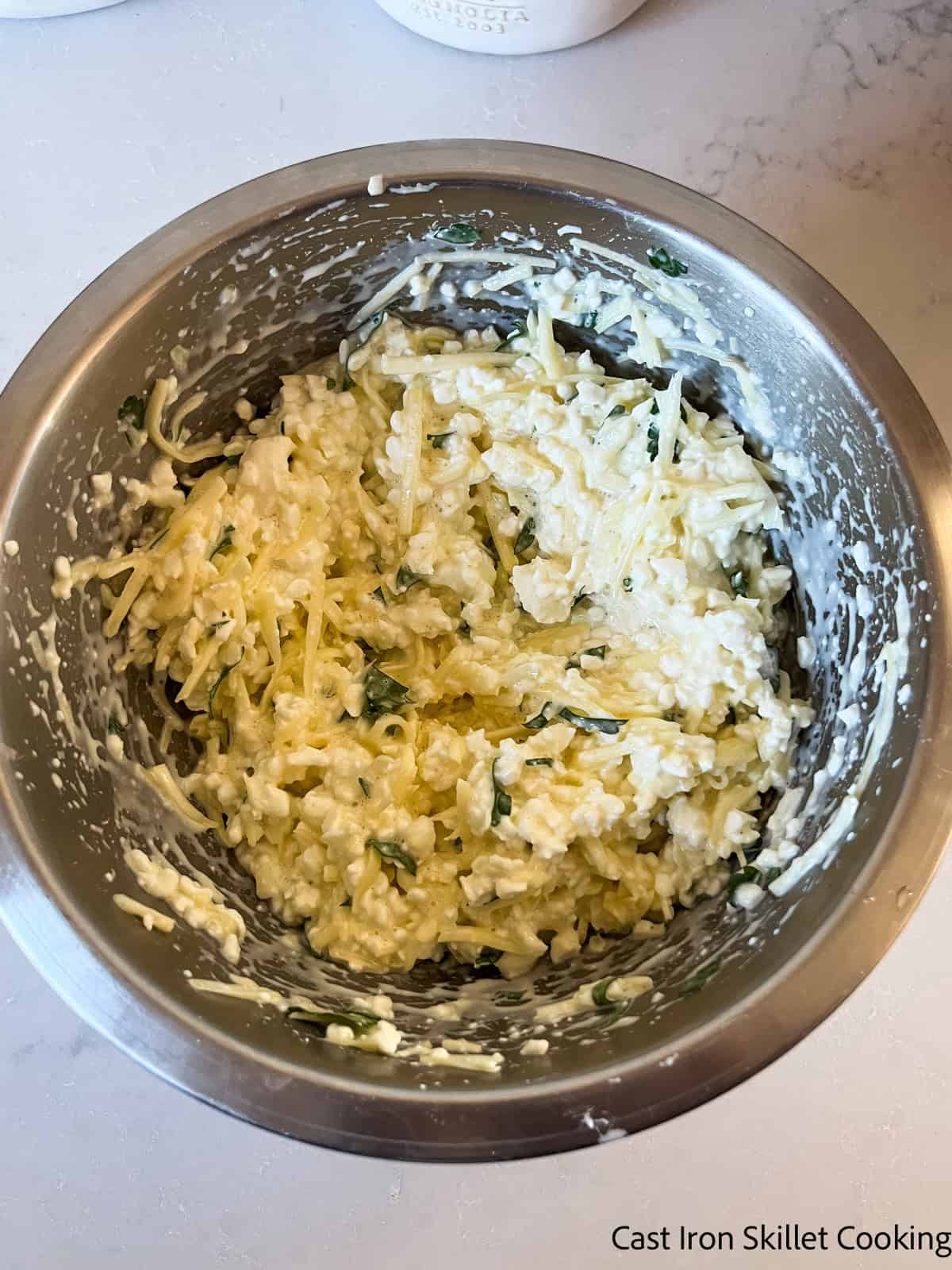 A mixing bowl with cheese mixture for lasagna.