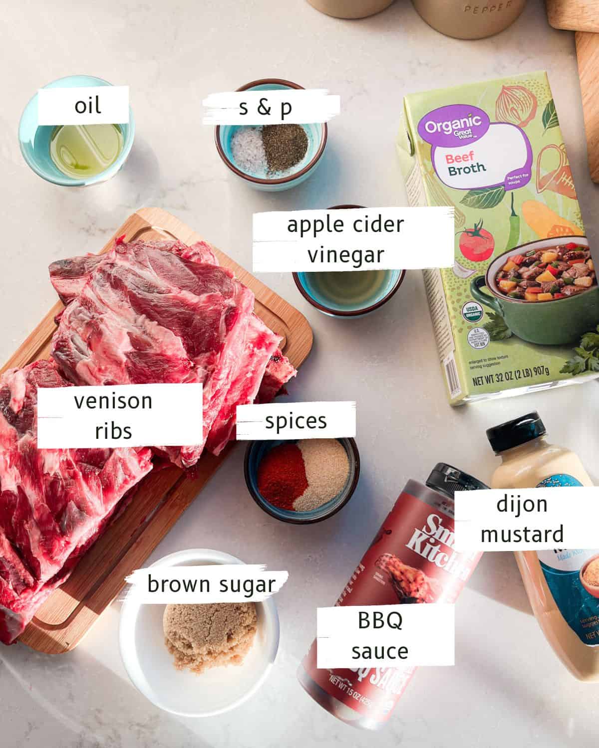 Braised venison ribs ingredients labeled on a white table.