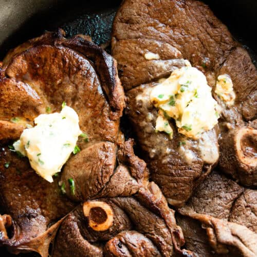 Garlic butter venison sirloin steaks in a cast iron skillet.