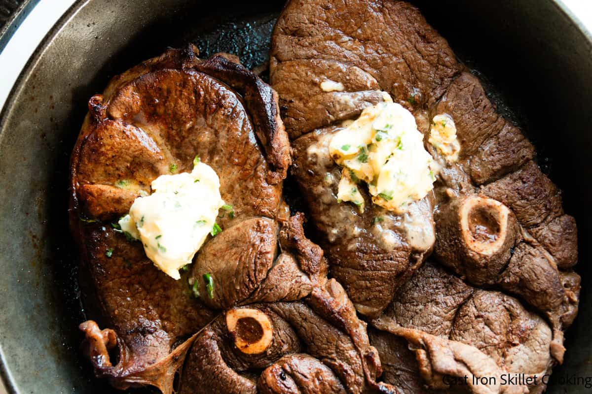 Garlic butter venison sirloin steaks in a cast iron skillet. 