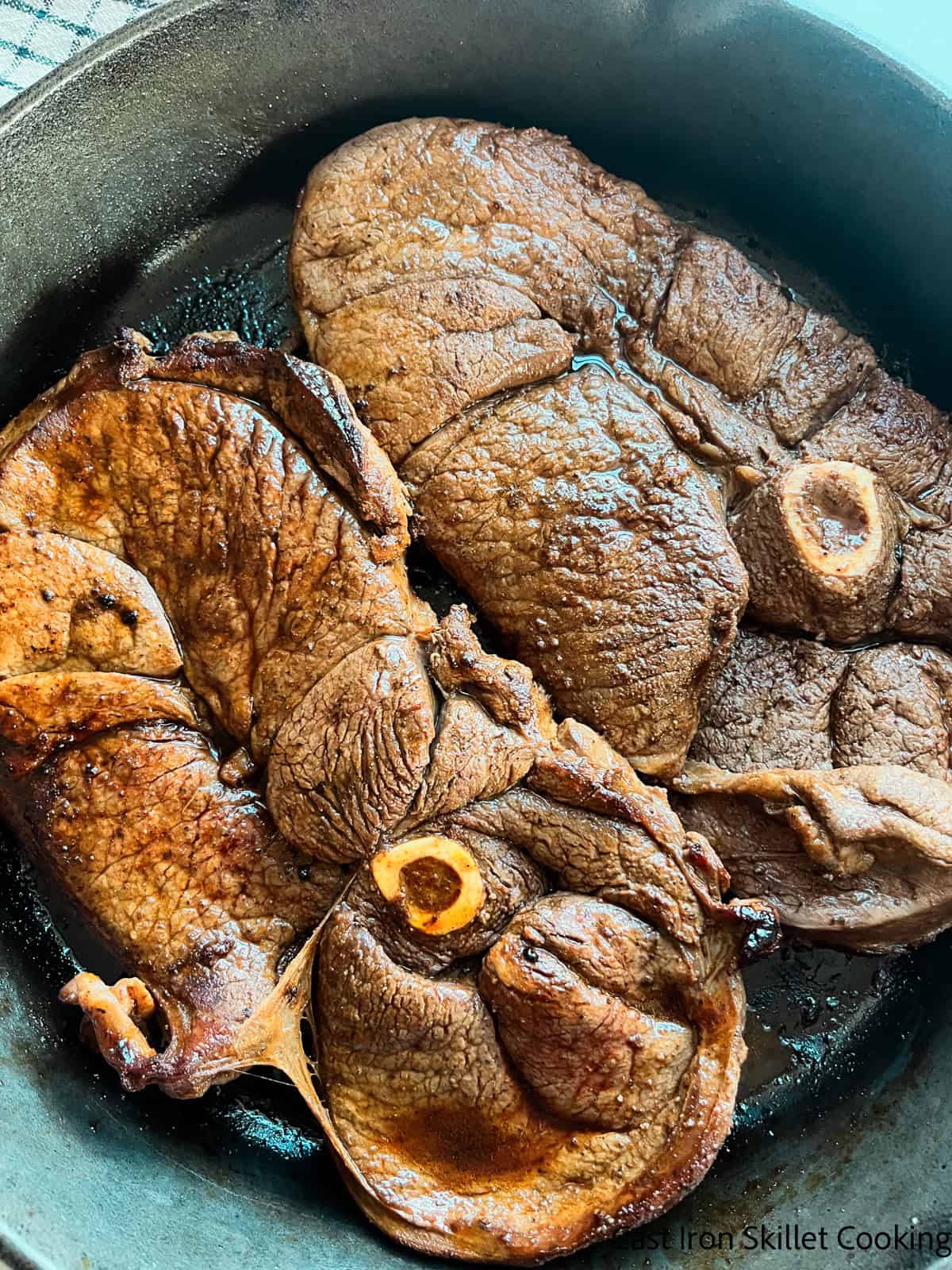 Venison sirloin steaks cooking in a cast iron skillet.
