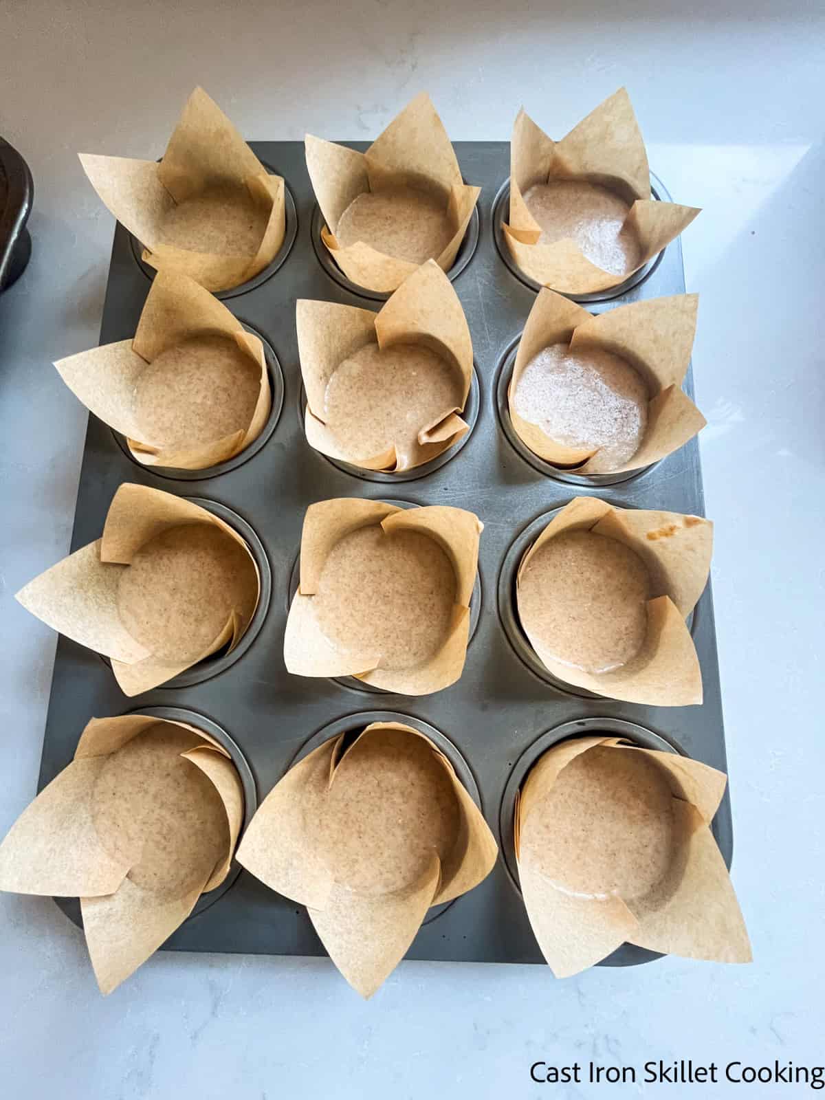 A muffing tin with liners filled with muffin batter.