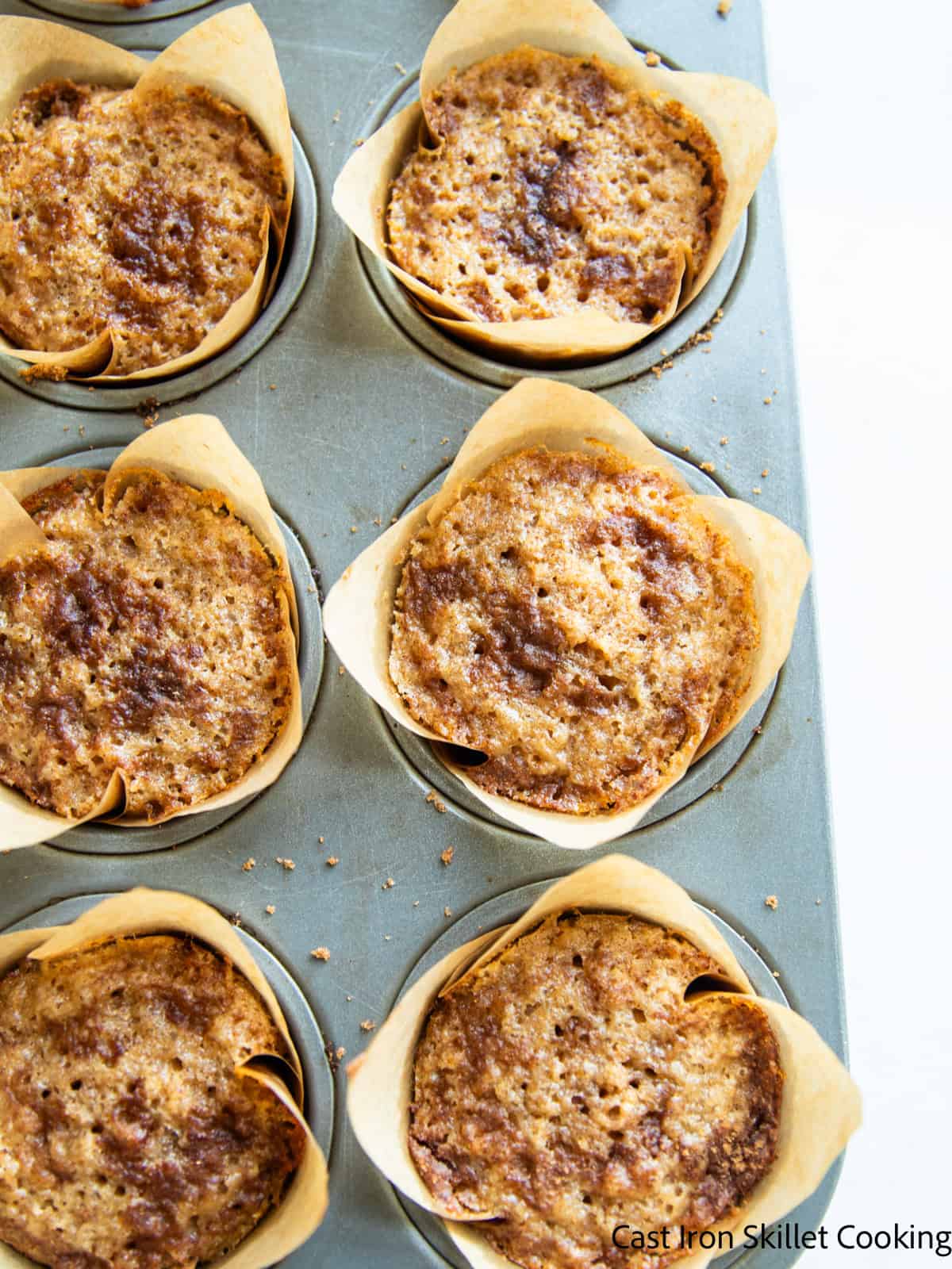 Looking down on a pan of whole grain cinnamon sugar muffins in brown paper liners.