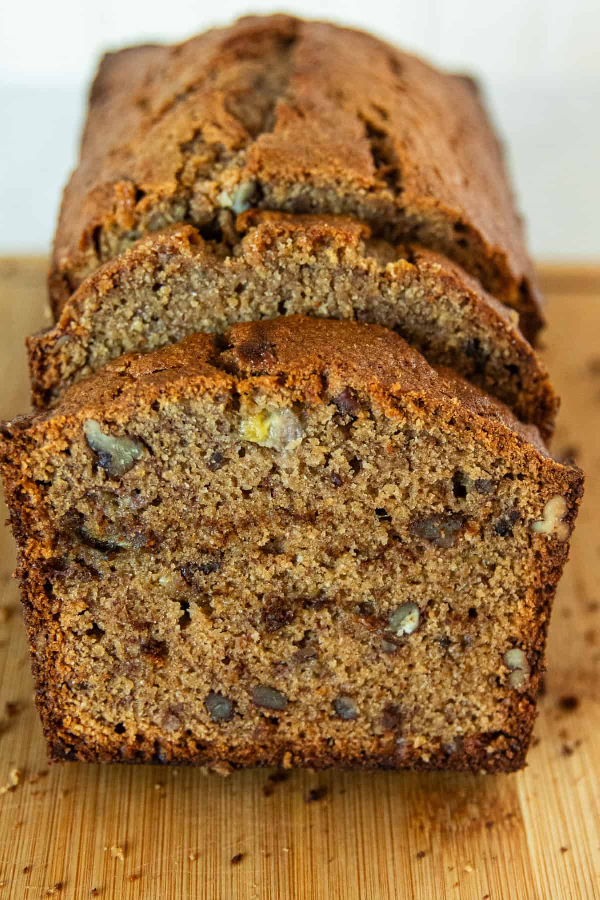 A sliced loaf of fresh milled banana bread on a wooden cutting board.