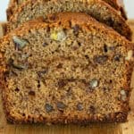 A sliced loaf of fresh milled banana bread on a wooden cutting board.