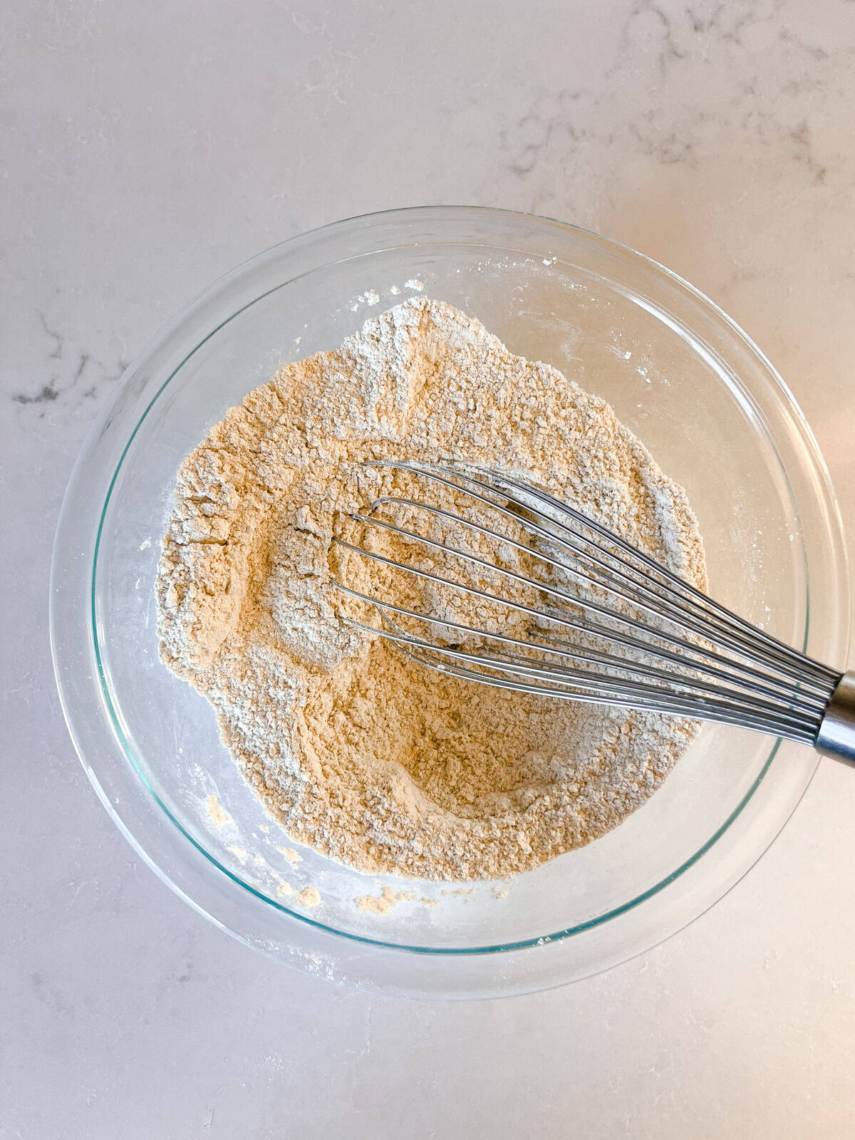Stirring dry ingredients together in a glass mixing bowl.