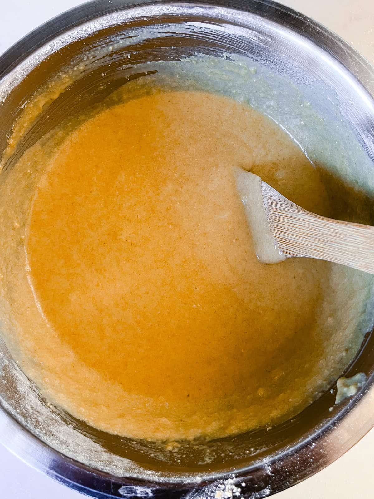 Mixing fresh milled cinnamon swirl batter with a wooden spoon.