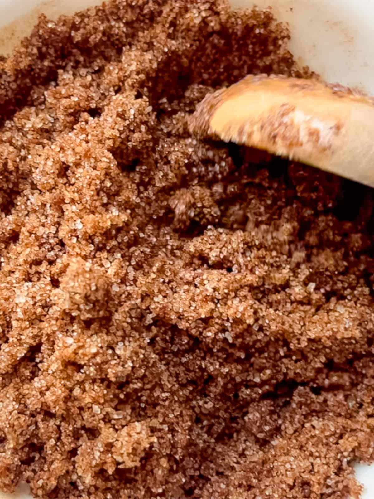 Mixing cinnamon and brown sugar together with a wooden spoon.