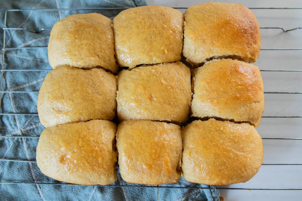 Buttery and fluffy hawaiian rolls cooling on a cooling rack.