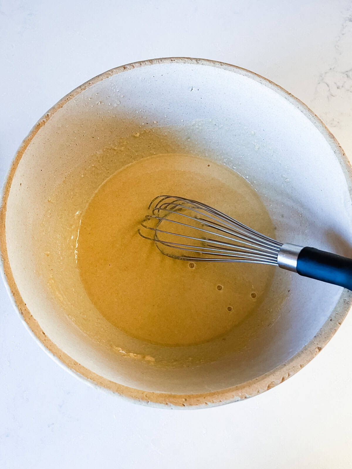 Whisking wet ingredients in a mixing bowl.