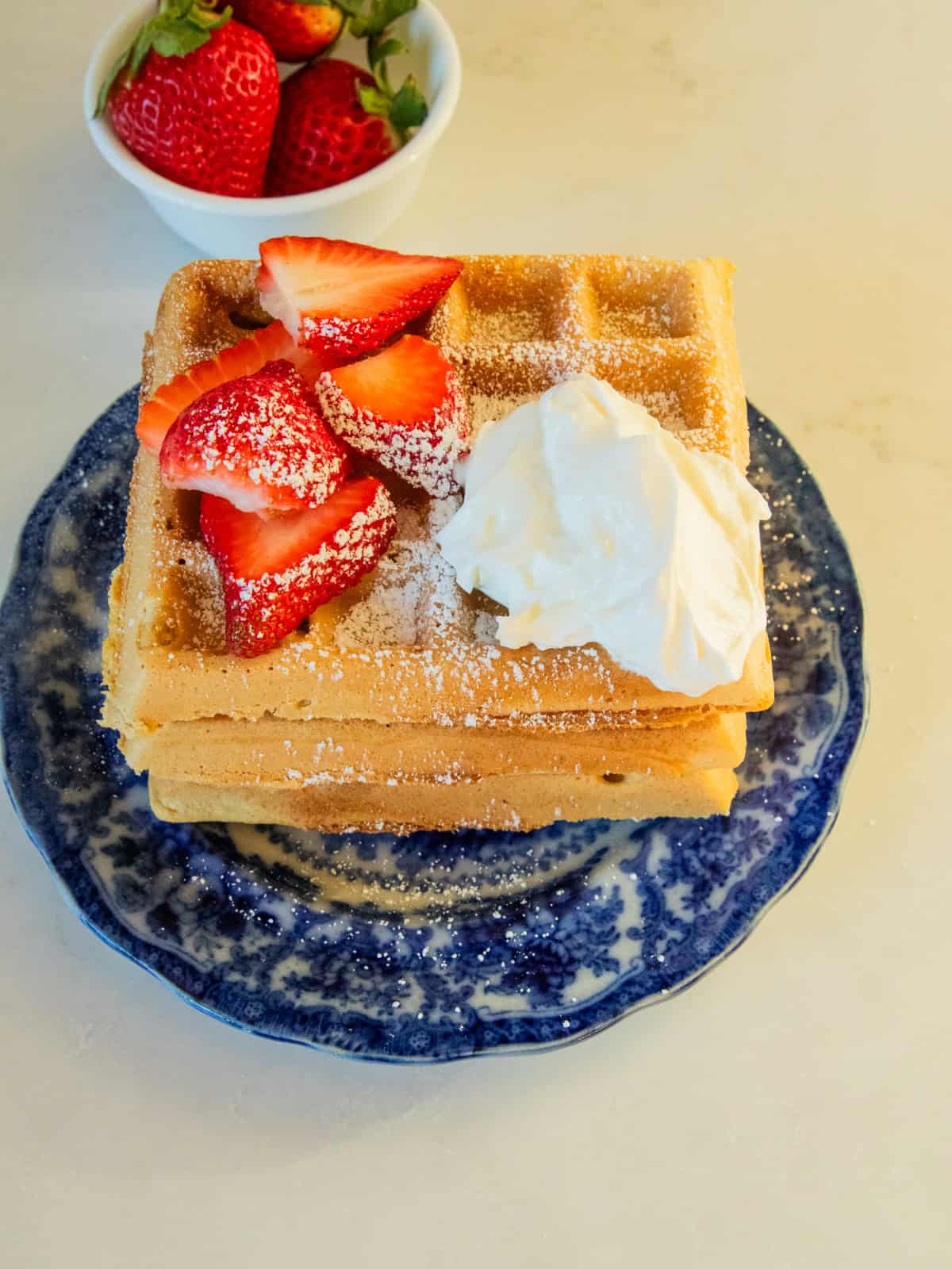 A stack of fresh milled waffles with fruit, whipped cream and powdered sugar!