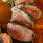 Slices of venison backstrap on a wooden board.