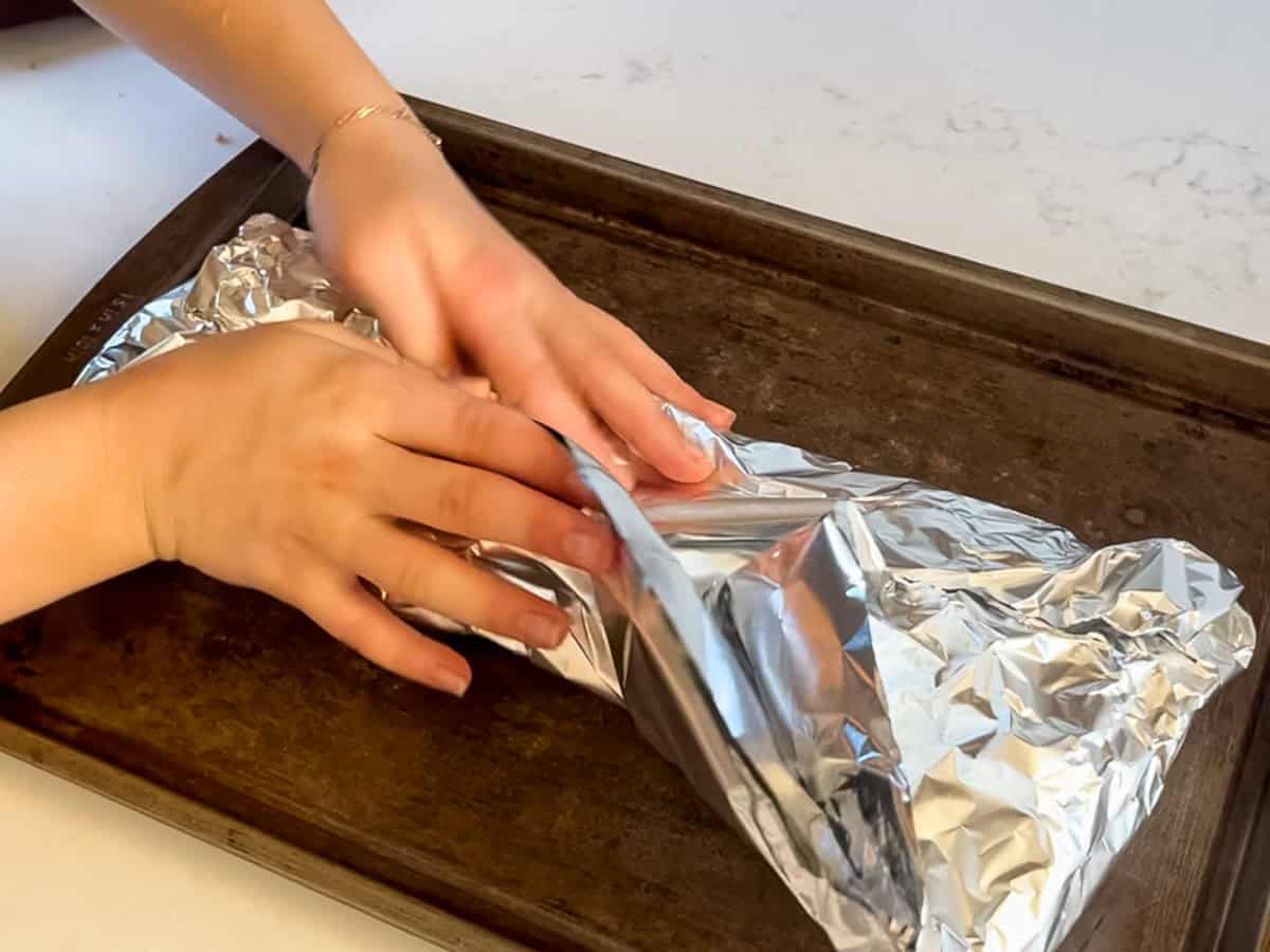 Wrapping the ribs in a piece of foil on a baking sheet.