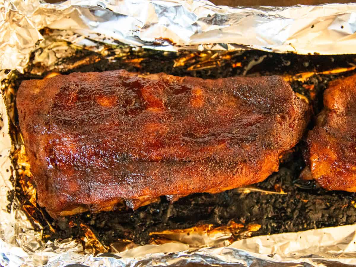 Pork baby back ribs right out of the oven on a piece of foil.