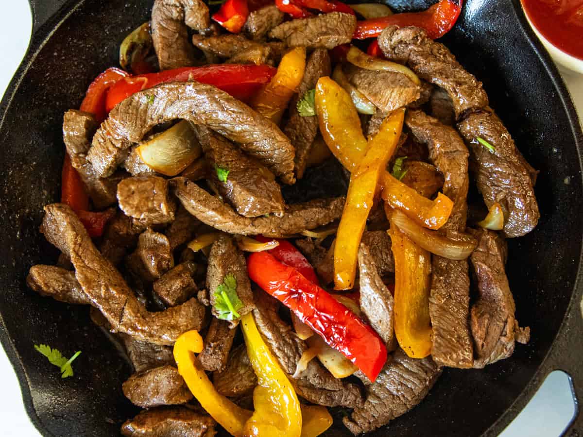 Venison fajitas in a cast iron skillet.