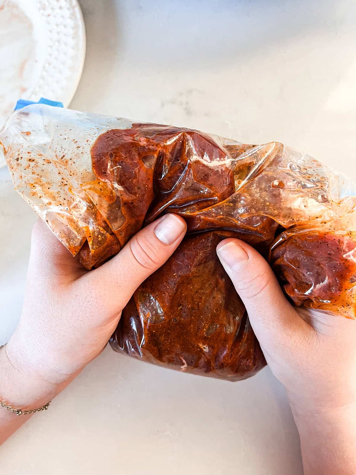 Kneading a plastic bag with venison and marinade in it.