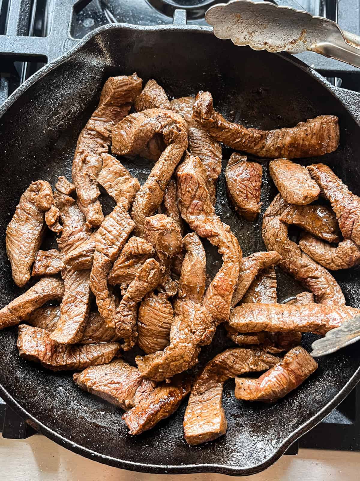 Cooking venison steak strips in a cast iron skillet.