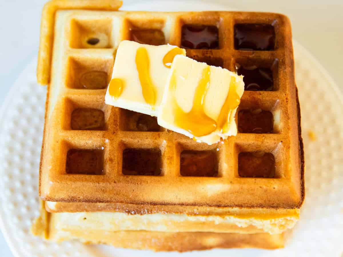 Fresh milled waffles with butter and maple syrup on top.