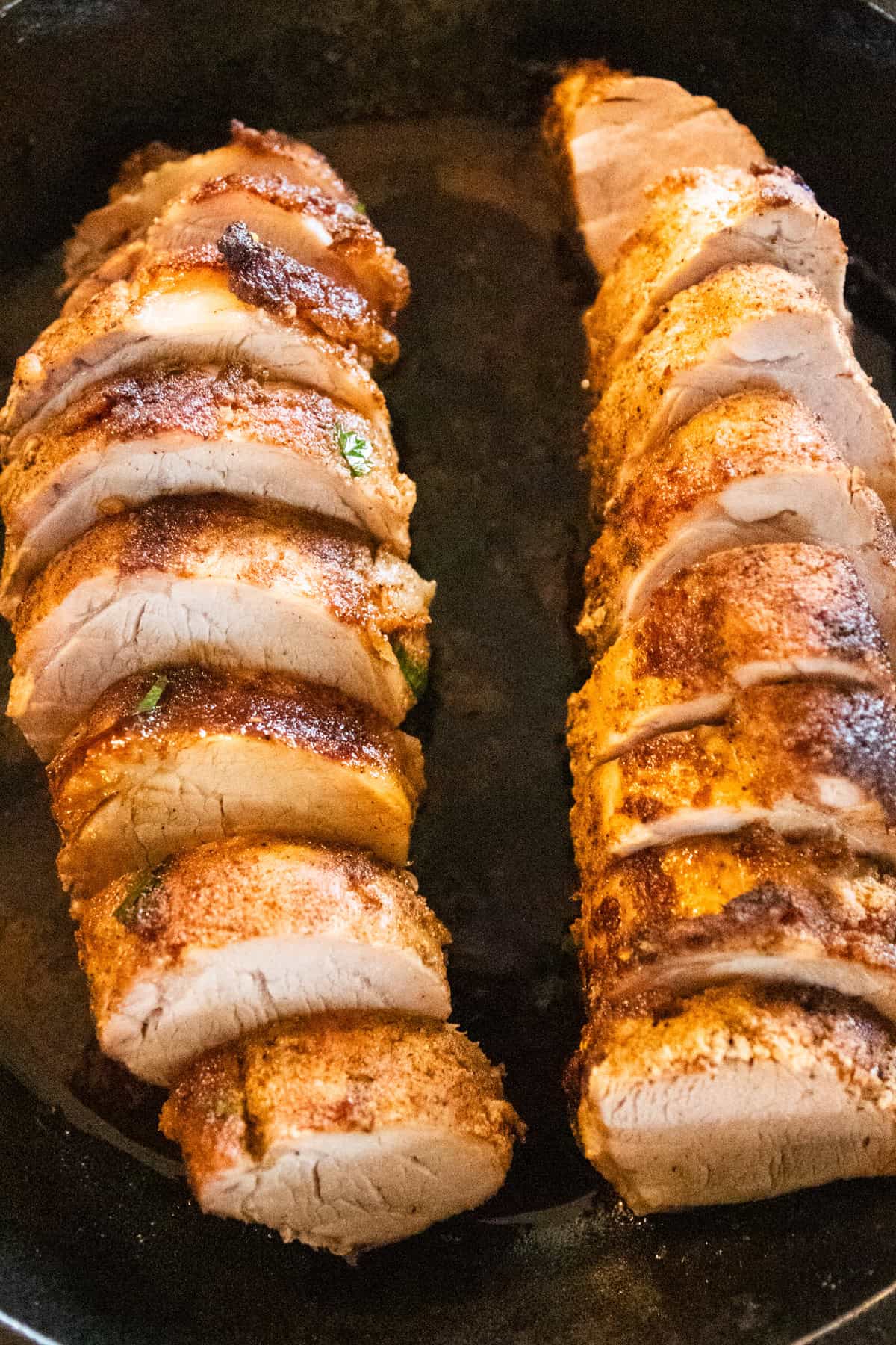 Sliced baked pork tenderloin in a cast iron skillet.