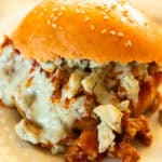 A buffalo chicken sloppy joe on a white plate with ranch and blue cheese.