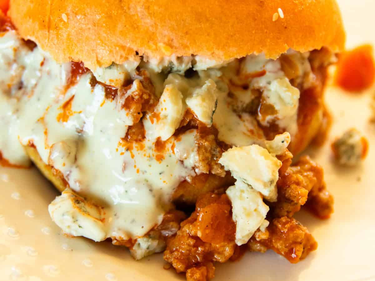 An up close look at a buffalo chicken sloppy joe on a hamburger bun with blue cheese and ranch.