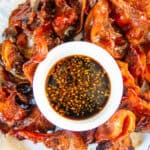 Pork jowl on a serving tray with a bowl of dipping sauce.