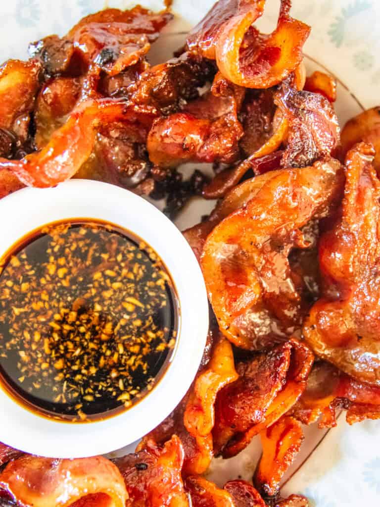 Crispy pork jowl on a serving platter with a bowl of dipping sauce.