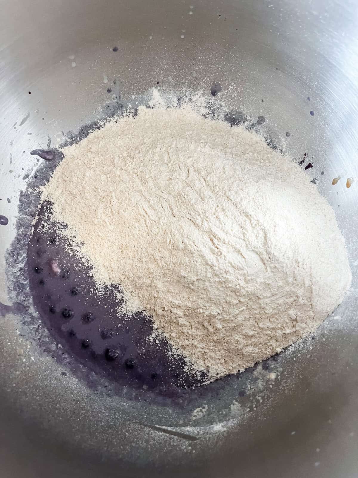 Adding flour to blueberry bagel dough mixture.