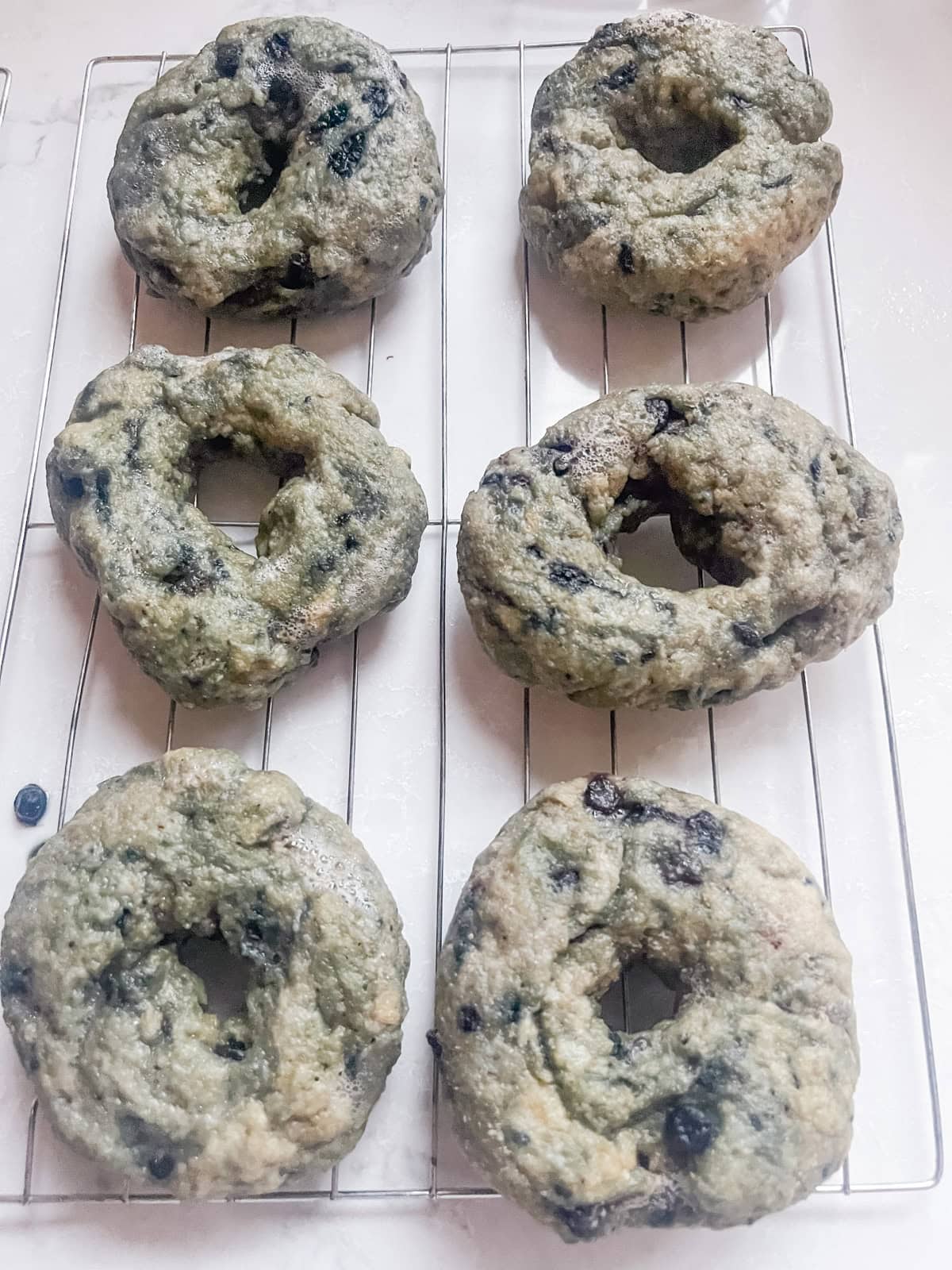 Blueberry bagels lined up on a striped towel.