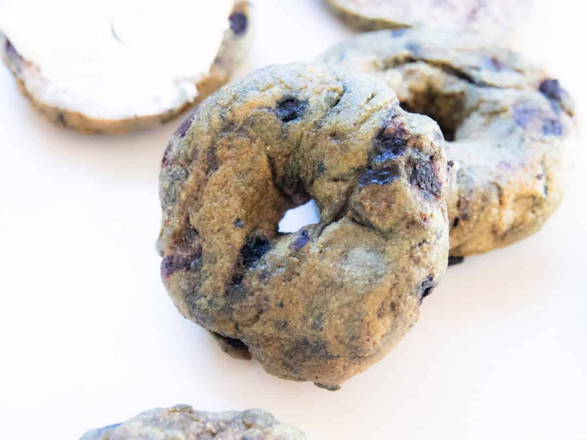 A freshly milled blueberry bagel with more bagels around it. 