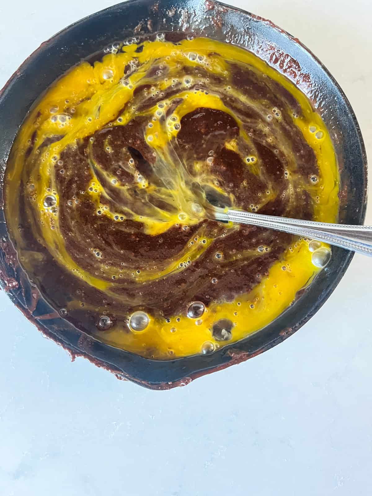 Stirring egg into brownie batter.