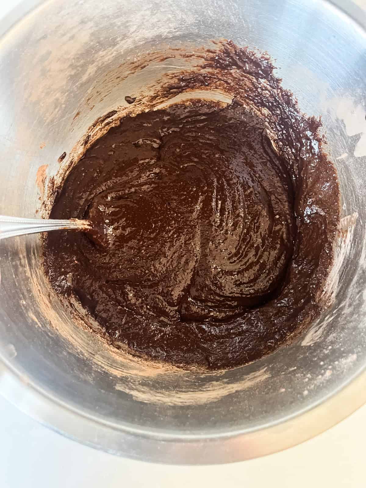 Mixing brownie batter in a metal mixing bowl.