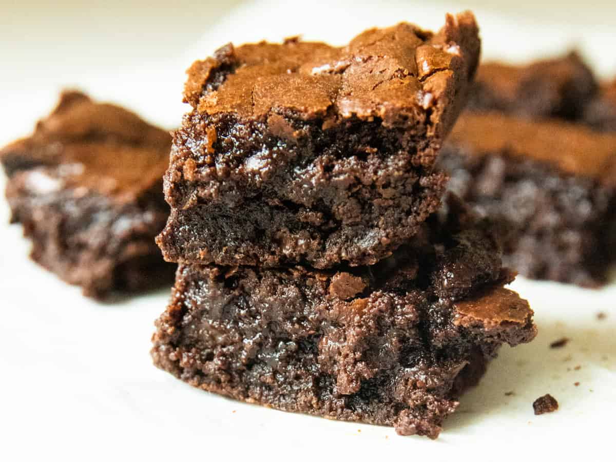 Two fresh milled flour brownies stacked with more brownies in the background. 