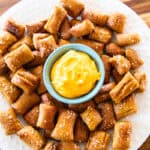 Fresh milled pretzel bites on a plate with a bowl of cheese sauce in the center.