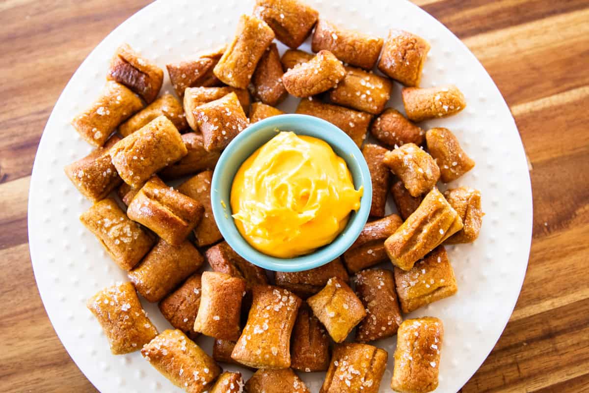 Fresh milled pretzel bites on a plate with a bowl of cheese sauce in the center.