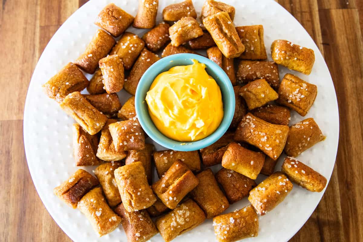 Chewy homemade pretzel bites with homemade cheese sauce in the middle on a serving plate.