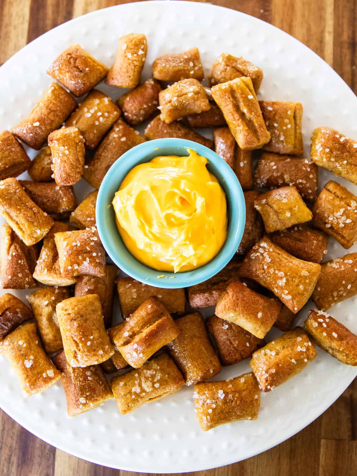 A plate of fresh milled pretzel bites with a bowl of cheese sauce in the center.