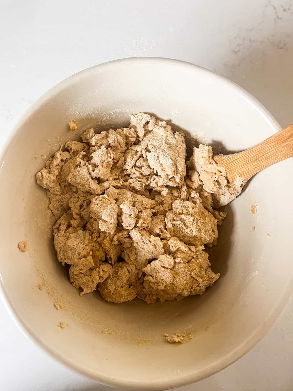Stirring freshly milled pretzel bites dough in a mixing bowl.