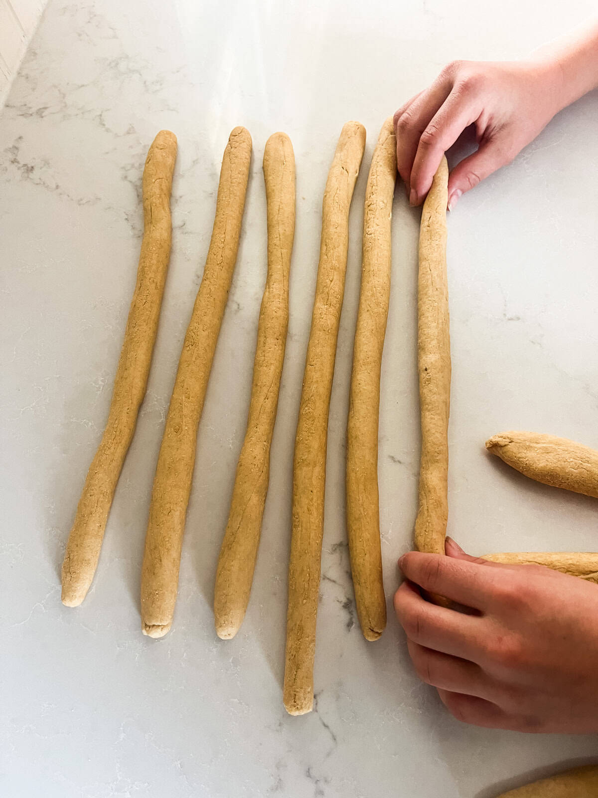 Rolling pretzel dough into long, skinny ropes.