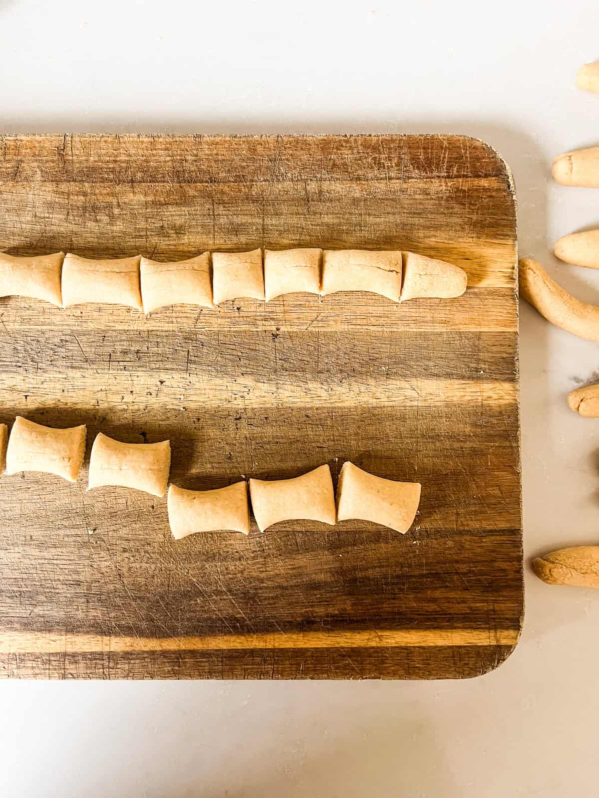 Chopping ropes of pretzel dough into bites on a wooden cutting board.