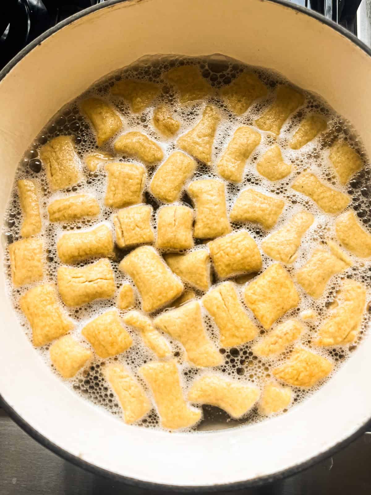 Boiling freshly milled pretzel bites in a pot of baking soda water.
